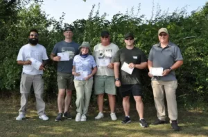 A group of people standing in front of a country hedge holding certificates